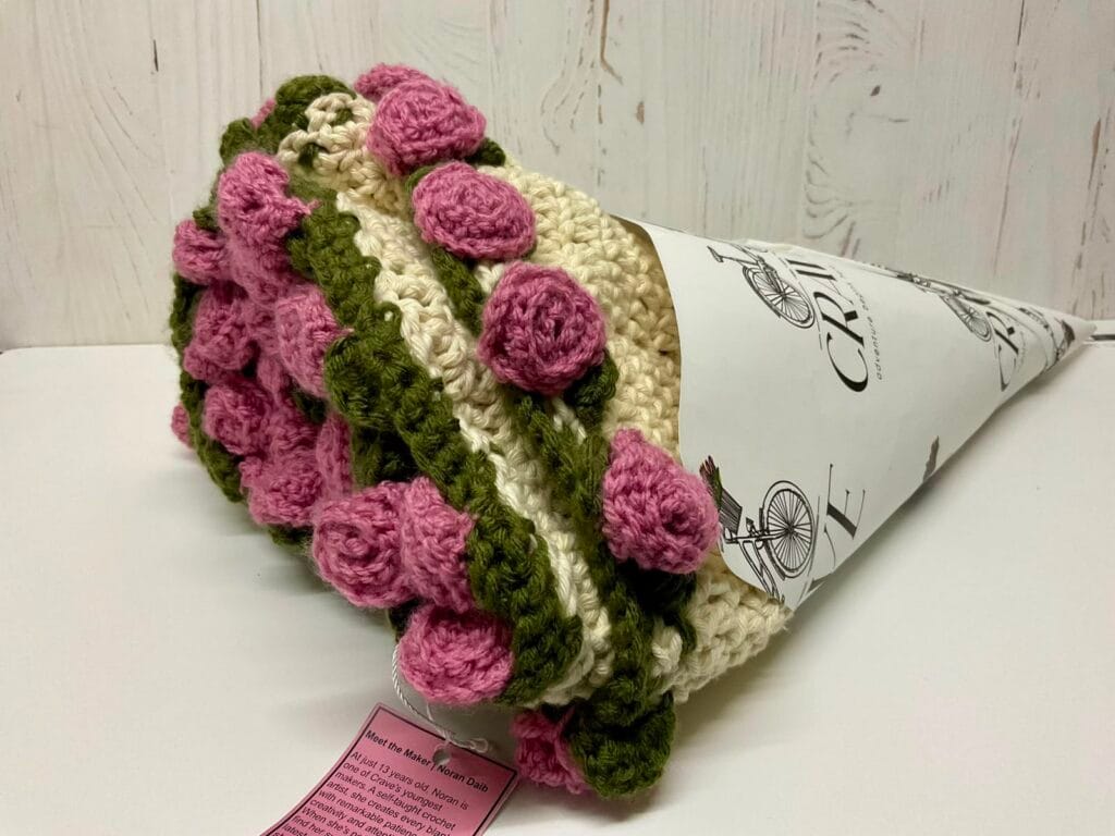 Cream and pink crochet baby blanket folded to look like a flower bouquet
